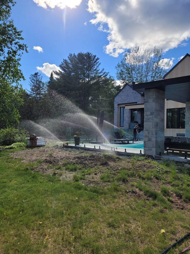 Système d’arrosage en fonctionnement près d’une résidence et de sa piscine